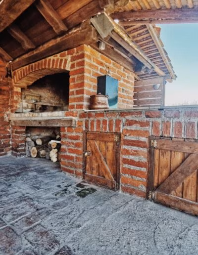 Vanjski prostor s rustikalnim zidanim roštiljem i drvenim elementima, smješten u kući za odmor Demode.