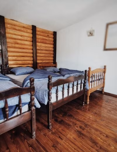 Soba s drvenim zidovima s dva drvena kreveta prekrivena plavom posteljinom i drvenim podom.