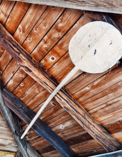 Drveni strop s ukrasnim gredama i starinskim fenjerom, te velikom drvenom lopaticom poput one za pečenje kruha.