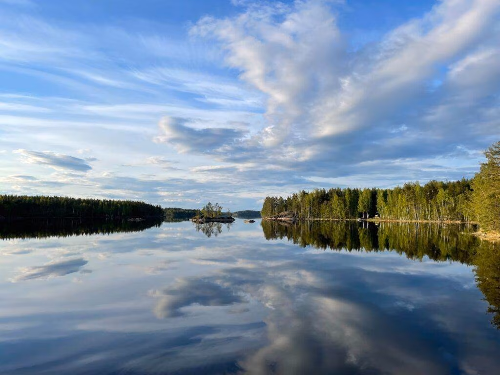 a body of water surrounded by trees and clouds