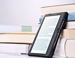 E-Book leaning against a stack of printed books.