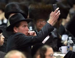 A man takes photos using his phone at a mass gathering of Satmar Hasidic Jews in New York