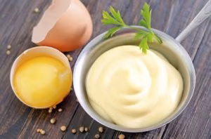 mayonnaise in metal spoon on wooden board
