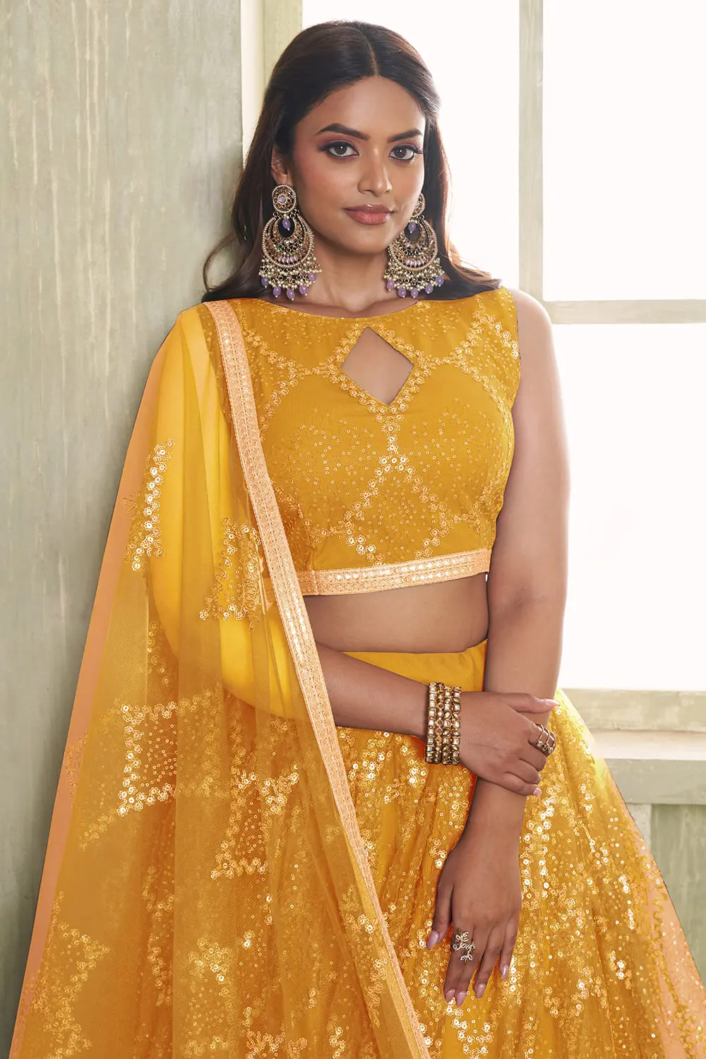 Close up of tone-to-tone thread work and glitter sequins on yellow net lehenga