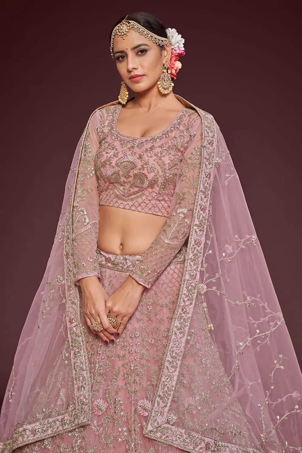 Rose gold soft net lehenga styled with embroidered blouse and dupatta