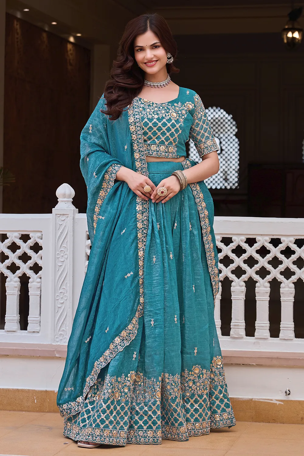 Close up of gold embroidery and sequins on teal blue silk lehenga