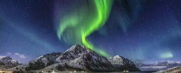 Green Aurora Borealis Over Snow Covered Mountain