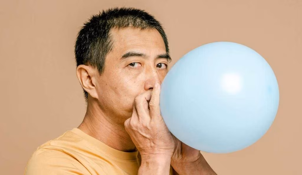 Uomo soffia in un palloncino