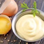 mayonnaise in metal spoon on wooden board