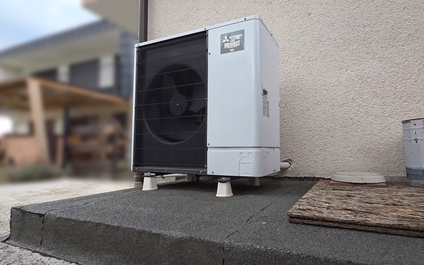 Zunanja enota toplotne črpalke Mitsubishi Electric ob fasadi hiše iz primerjave